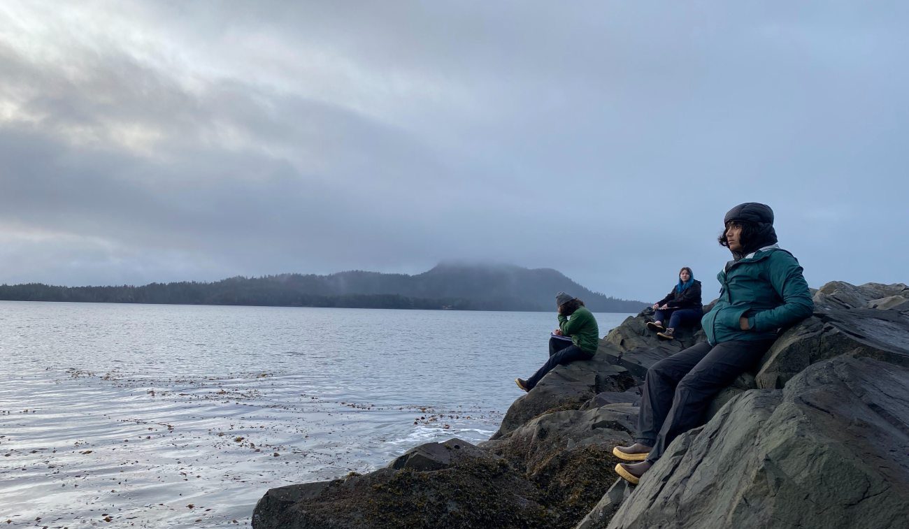 Students and faculty sit on rocks in Sitka Alaska